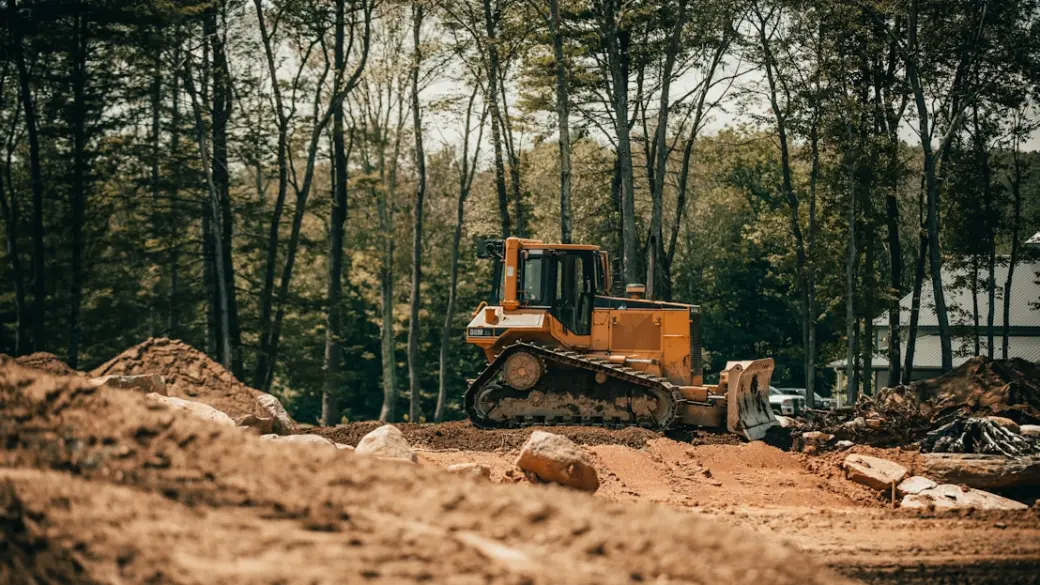 Pásový dozer srovnává terén na pozemku u lesa